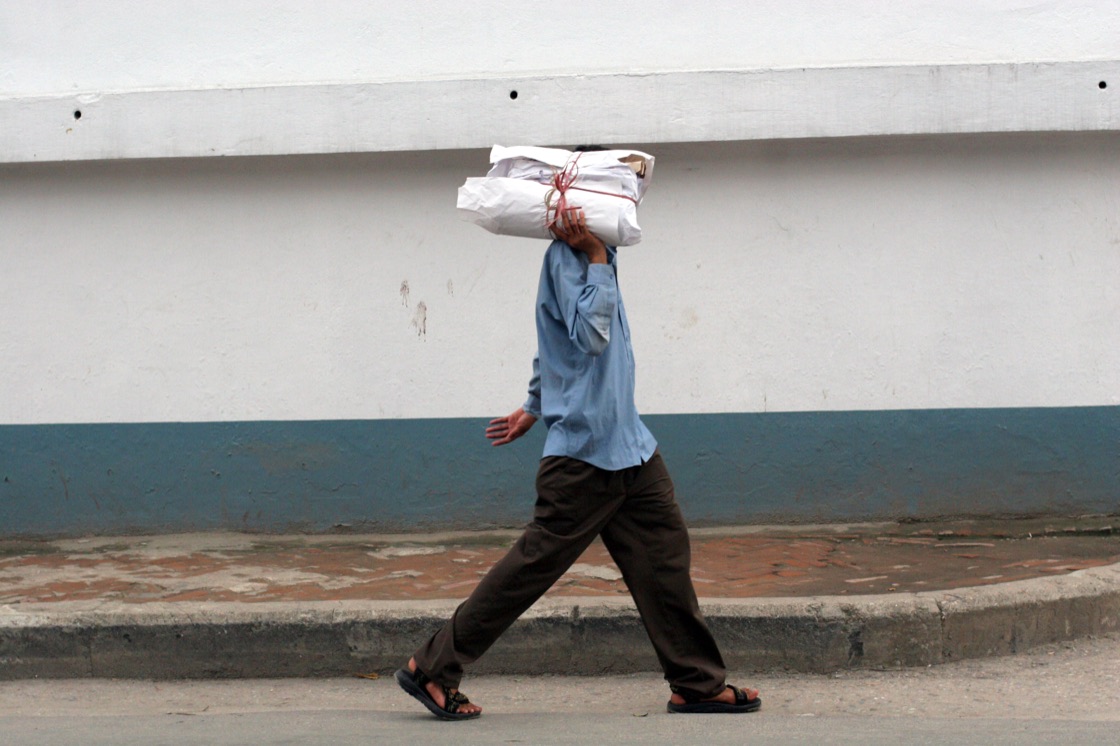 T.P. Mishra carries a bundle of newspapers on his shoulder through a Kathmandu street